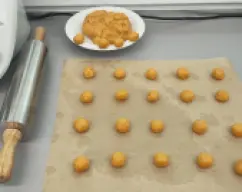 Step <p>Formamos sobre papel vegetal las bolitas de masa que luego estiraremos.Si queremos podemos poner un plato sobre la tapa del vaso y pesar cada una para que sean más o menos iguales sacando el peso de Thermomix.</p> illustration