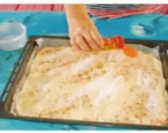 Step <p>Extiéndela sobre la bandeja de horno y espolvorea con azúcar,canela la superficie y reparte los chicharrones sobre ella.Hornea más menos una media hora con el horno arriba y abajo hasta que se dore.</p> illustration