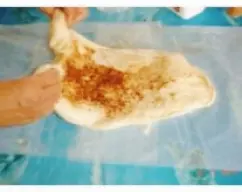 Step <p>Extiende la masa sobre el papel vegetal con un rodillo Ve añadiendo a pellizcos poco a poco parte de la manteca y el azúcar.</p><p>Dobla la masa de nuevo,estira y sigue añadiendo manteca, ,canela y azúcar que se vaya integrando toda.</p><p><br></p><p><br></p> illustration