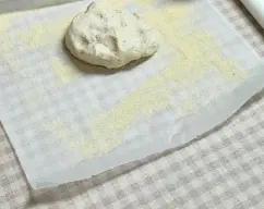 Step <p>Apretamos la masa para hacer una bola y echamos sobre papel vegetal la sémola de trigo duro y extendemos la masa sobre ella a nuestro gusto de gruesa con un rodillo.</p> illustration